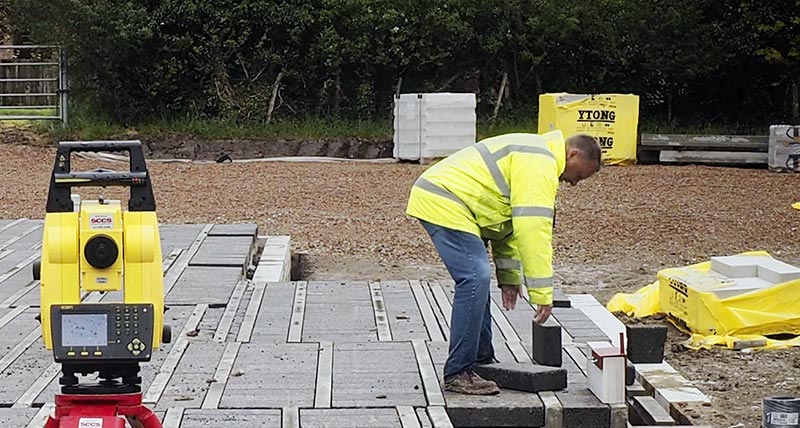 Construction worker on construction site is using a Leica iCON total station to lay the foundation for a building